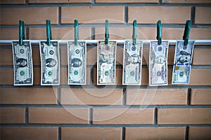 Concept of money laundering - dollars are drying on lath on on brick wall background