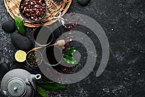 Set of black, green, fruit and herbal tea on black stone background. Tea in teapot and cup. Top view.