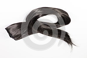 A set of black hair extensions of reddish brunette curly hair on a beauty shop table