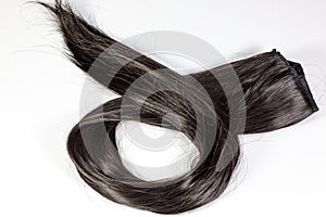 A set of black hair extensions of reddish brunette curly hair on a beauty shop table