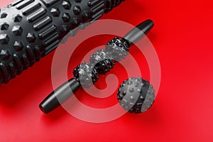 Set of Black lumpy foam massage roller, body roller, rubber ball on red background
