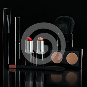Set black makeup. Lipstick, mascara, powder, brush, pencil. On a black background.