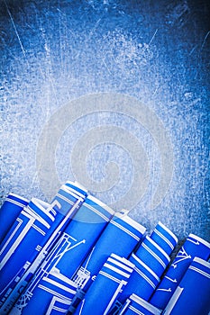 Set of blue rolled construction drawings on metallic background