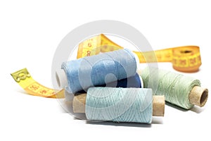 A set of blue threads for sewing and a centimeter on a white background