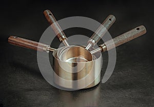 Set of Brass Measuring Cups with Wood Handles with Hanging Hole Design on dark background