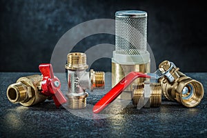 Set of brass pipe connectors ondark background photo