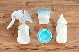 Set of breast pump and bottles with breast milk for baby on wooden background. Maternity and baby care concept.