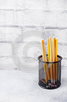 Set of bright simple pencils in a black stand on a gray table, copy space