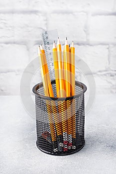 Set of bright simple pencils in a black stand on a gray table, copy space