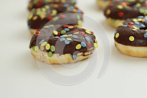 Set of Brown chocolate donut decorated with smarties isolated on white background side view. Fried dough confection, dessert food