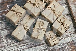 Set of brown gift boxes on wooden background. Wrapped in craft paper and tied by hemp cord. A lot of parcels.