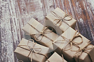 Set of brown gift boxes on wooden background. Wrapped in craft paper and tied by hemp cord. A lot of parcels.