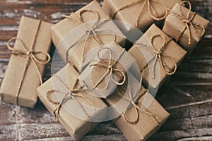 Set of brown gift boxes on wooden background. Wrapped in craft paper and tied by hemp cord. A lot of parcels.