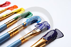 Set of brushes with different paints on white background, closeup. Rainbow colors