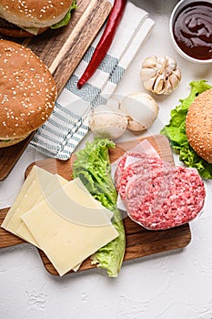 Set of burger raw ingredients and ground beef on white textured background, topview