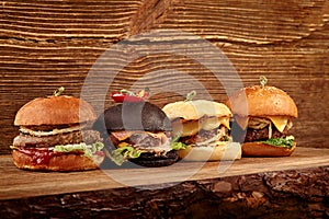 Set of burgers with meat, cheese, tomatoes, mayonnaise on wooden table and background. Space for text.