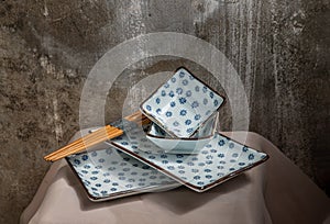 Set of Ceramic Plates, Bowls and Wooden chopsticks on pink table cloth