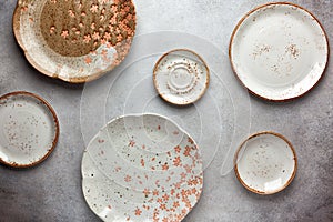 Set of ceramic round bowls and plates on vintage grey background. Flat lay