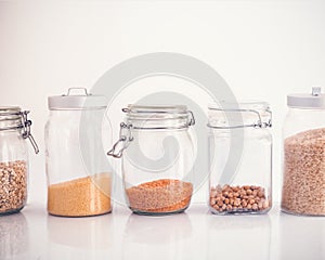 Set of cereals in a glass jar on a white background, rice chickpeas lentil oats millet healthy food and diet concept