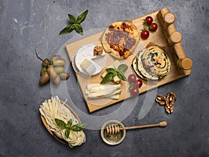 A set of cheeses. Halumi, cheese sticks, Suluguni, Camembert,  fresh soft white burrata cheese ball, mozzarella on a wooden board