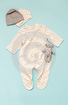 Set of children`s clothes for newborns on a blue background for a girl: a body with a long sleeve and a selection of caps. spring