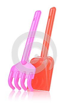 A set of children's toys for playing in the sandbox. Colored rake and shovel made of plastic, isolated on a