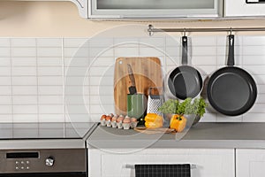 Set of clean cookware, utensils and products on table in modern kitchen