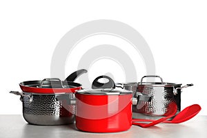 Set of clean cookware and utensils on table against white background