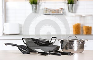 Set of clean cookware and utensils on table in kitchen.