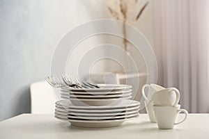 Set of clean dishware and cutlery on white table indoors. Space for text