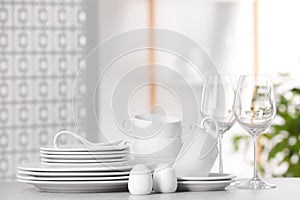 Set of clean dishware and glasses on light grey table, space for text