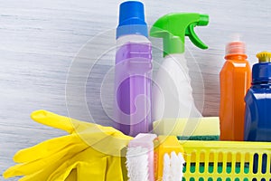 Set of cleaning products, stands in a yellow basket, on a light background and yellow rubber gloves for cleaning