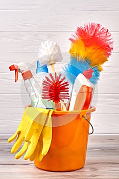 Set of cleaning supplies in colorful bucket.