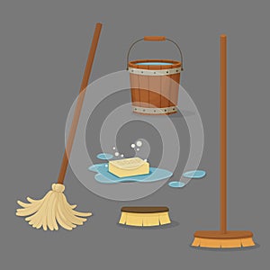 Set of cleaning tools. Floor brush with a wooden handle, mop, an old bucket full of water and soap in a puddle with bubbles.