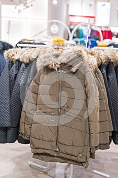 Set of clothes, coat on the rack clothing shop interior on background. Winter jackets in a store. vertical photo