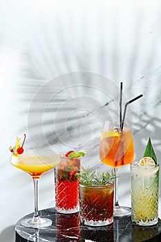 Set cocktails on marble table and light background. five kinds of colorful summer cocktails in glasses and shadow of tropic leaf