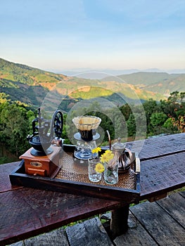 The set of coffee dripper makers on a wooden table and a blurred mountain background photo
