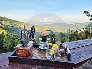The set of coffee dripper makers on a wooden table and a blurred mountain background photo