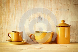 Set of coffee mugs and old jar over wooden rustic table. filtered image