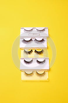Set, collection of black false eyelashes on trendy bright yellow background, lashmaker concept, beautician industry, beauty salon
