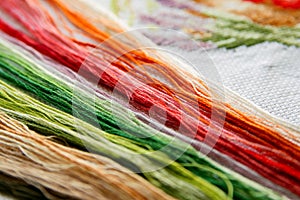 Set of colored bright threads for embroidery on a embroidered canvas.