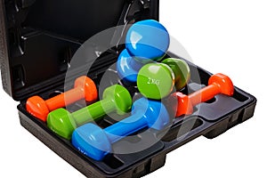 A set of colored isolated dumbbells for sports on a white background is stacked in a black case