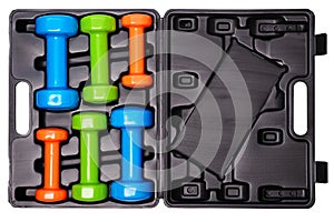 A set of colored isolated dumbbells for sports on a white background is stacked in a black case from above