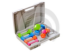 A set of colored isolated dumbbells for sports on a white background is stacked in a gray case