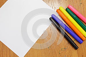 A set of colored markers and a sheet of white paper on the table