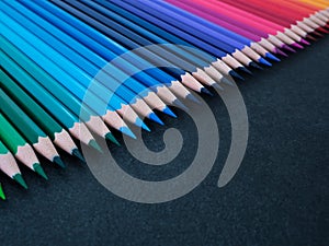 Set of colored pencils arranged in a row on slate background