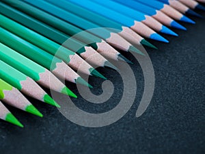 Set of colored pencils arranged in a row on slate background