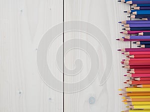 Set of colored pencils arranged in a row on wooden background