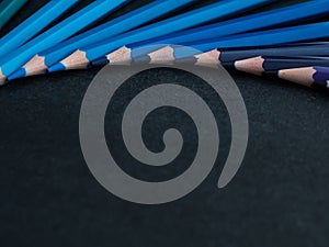 Set of colored pencils arranged in a wheel on slate background