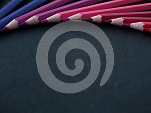 Set of colored pencils arranged in a wheel on slate background